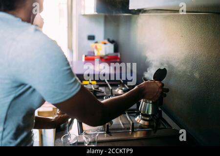 Gros plan de la femme faisant du café sur la cuisinière dans la cuisine