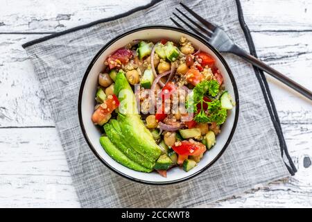 Bol de salade de quinoa végétarienne avec pois chiches, avocat, concombre, tomate, oignon et persil Banque D'Images