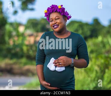 Femme enceinte afro-américaine portant de jolies chaussettes blanches pour bébé son ventre Banque D'Images