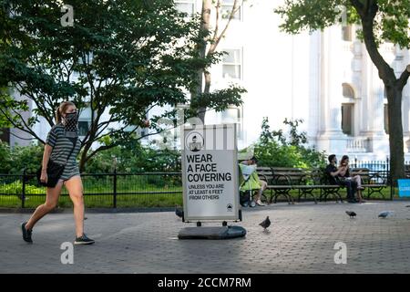 22 août 2020 : un panneau se trouve au Madison Square Park avec des directives sur les EPI et les distances sociales pendant qu'une femme passe devant porter un visage couvrant à Manhattan, New York. Crédit obligatoire : Kostas Lymperopoulos/CSM Banque D'Images