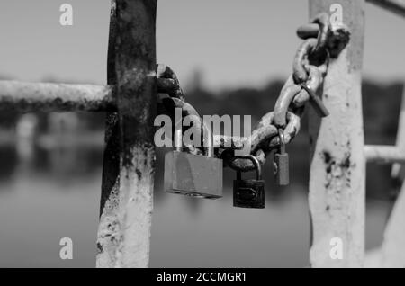 Plusieurs cadenas pendent d'une ancienne chaîne. Cadenas de mariage enchaînés au pont de la ville. Symbole de l'amour et de la tradition de mariage ancienne. Vieux rouillé chéri l Banque D'Images