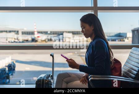 Téléphone d'aéroport une femme de voyage utilisant un téléphone mobile dans un salon de classe affaires attendant un vol d'avion envoyant des SMS sur un smartphone. Technologie et Banque D'Images