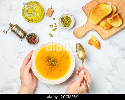 Soupe végétarienne à la crème, purée de potiron, carottes et pommes de terre avec huile d'olive, graines et épices sur une table en marbre dans une assiette blanche. Mise au point sélective Banque D'Images