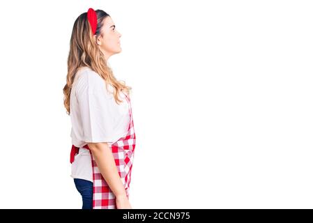 Jeune femme caucasienne portant un tablier regardant sur le côté, se détendre profil poser avec le visage naturel avec le sourire confiant. Banque D'Images