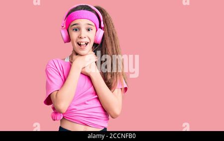 Adorable enfant hispanique fille portant des vêtements de gym et utilisant le casque criant et suffoquer parce que la douleur de strangle. Problème de santé. Asphyxiate et suic Banque D'Images