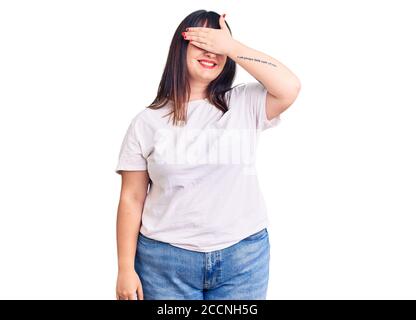 Jeune femme de taille plus portant des vêtements décontractés souriant et riant avec la main sur le visage couvrant les yeux pour la surprise. Concept aveugle. Banque D'Images