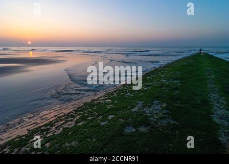 Pêcheur à la fin d'un brise-lames au coucher du soleil à côté de la plage de la ville d'Ostende (Ostende), Flandre Occidentale, Belgique. Banque D'Images