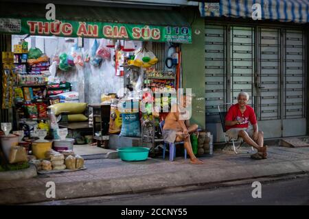 Restaurant d'animaux de compagnie traité ouvert la nuit. Des hommes d'âge pieds nus bavardent, bavardent devant la boutique, assis sur des chaises. Ho chi Minh, Saigon, Vietnam Banque D'Images