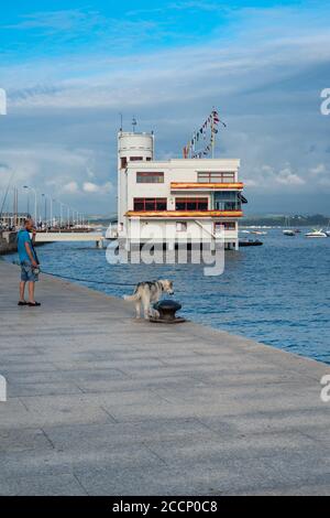 Jeune homme audacieux marchant un husky sibérien dans la baie de Santander, en Espagne. Husky sibérien regardant la mer à Puerto Chico, Santander, Cantabrie. Banque D'Images