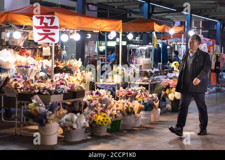 Homme passant par une cabine de fleurs la nuit. Marché de rue. Homme qui revient de son travail ou qui a dîné avec des collègues ou des amis. Automne ou hiver. Corée Banque D'Images