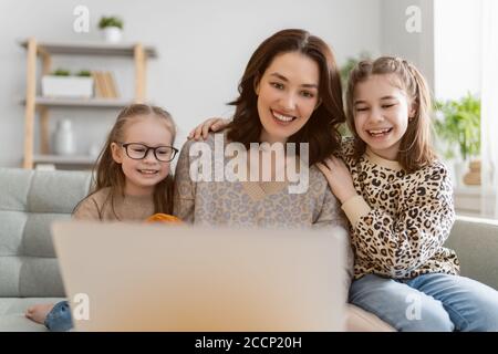 Famille heureuse et aimante. Jeunes filles et mères utilisant un ordinateur portable. Maman drôle et les enfants adorables s'amusent à rester à la maison. Banque D'Images