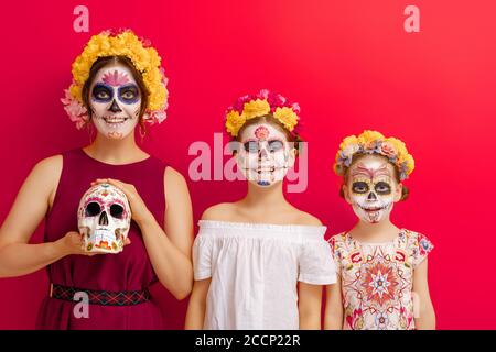 Des zombies adorables dans des couronnes de fleurs posant sur fond jaune. Une famille heureuse avec un maquillage créatif pour Halloween. Les filles célèbrent pour la fête mexicaine du Banque D'Images