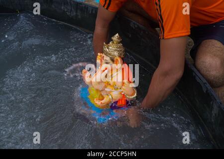 Ganesh idol immersion dans les restrictions de la pandémie de covid 19. Ganpati Visarjan en Homme fait des gens d'étang avec masque -Mumbai, Maharashtra / Inde. Banque D'Images