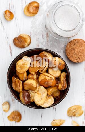 Gros grains frits croustillants avec sel dans un bol, sur une table. Vicia faba. Mise au point sélective Banque D'Images