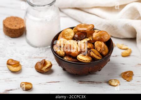 Gros grains frits croustillants avec sel dans un bol, sur une table. Vicia faba. Mise au point sélective Banque D'Images