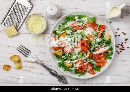 Salade César saine au saumon salé (truite), à l'iceberg ou à la laitue, au parmesan, aux tomates, aux croûtons de pain et à la sauce gastronomique. Mise au point sélective, haut Banque D'Images