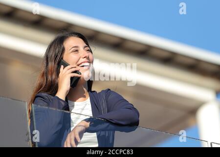 Heureux propriétaire d'appartement appelant sur le téléphone regardant loin dans un balcon Banque D'Images