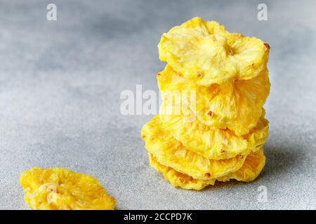 Anneaux d'ananas jaunes séchés sur fond de béton gris ou de pierre. Collation saine et utile. Mise au point sélective, espace de copie Banque D'Images
