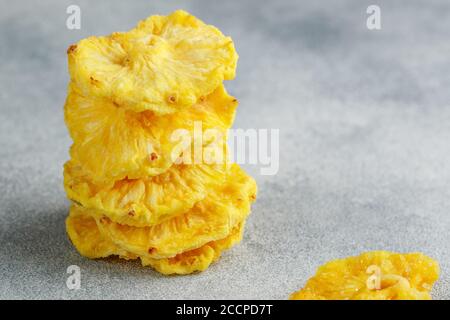 Anneaux d'ananas jaunes séchés sur fond de béton gris ou de pierre. Collation saine et utile. Mise au point sélective, espace de copie Banque D'Images