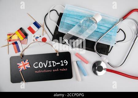 Restrictions et règles COVID-19. Masques médicaux, désinfectant pour les mains et stéthoscope. Tableau de craie et drapeau britannique sur une table blanche Banque D'Images