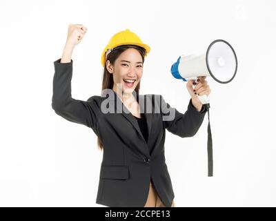 Jeune femme asiatique ingénieur portant un costume et un casque de sécurité jaune tenant un mégaphone et levez la main avec succès souriant isolé sur fond blanc. Banque D'Images