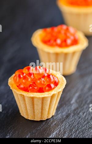 Caviar rouge de saumon dans un tartelet sur fond sombre. Concept d'alimentation saine. Fruits de mer. Hors-d'œuvre gastronomique. Mise au point sélective Banque D'Images