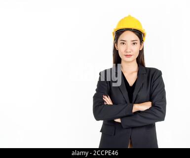 Jeune femme d'affaires asiatique portant un costume noir et un casque de sécurité jaune debout avec ses bras pliés. Portrait d'une femme ingénieure qui a l'air confiante de l'iso Banque D'Images