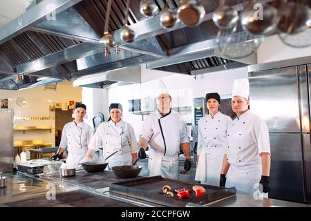 Cinq chefs portant des uniformes posant dans une cuisine . Banque D'Images
