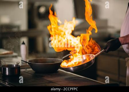 Cuisine moderne. Les cuisiniers préparent les repas sur la cuisinière dans la cuisine du restaurant ou hôtel. L'incendie dans la cuisine. Banque D'Images