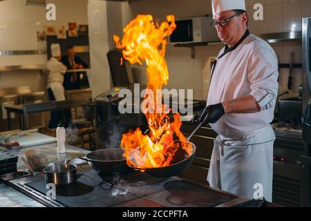 Cuisine moderne. Les cuisiniers préparent les repas sur la cuisinière dans la cuisine du restaurant ou hôtel. L'incendie dans la cuisine. Banque D'Images