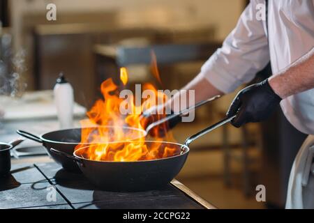 Cuisine moderne. Les cuisiniers préparent les repas sur la cuisinière dans la cuisine du restaurant ou hôtel. L'incendie dans la cuisine. Banque D'Images