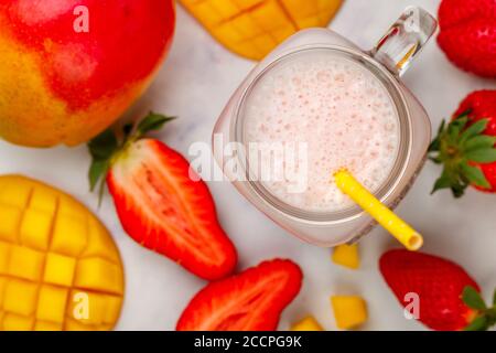 Smoothie ou milkshake à base de fraises fraîches, de mangue, de yaourt ou de lait et de glaçons dans un pot Mason placé sur une table en marbre. Concept de la vitamine dri saine Banque D'Images