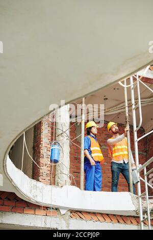 Contremaître multiethnique vérifiant les tuyaux de gaz métalliques dans le mur du bâtiment en construction Banque D'Images