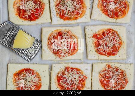 Cuisson de tartes maison de pâte feuilletée avec tomate, oignon, fromage mozzarella et thym. Mini pizza. Mise au point sélective, vue de dessus Banque D'Images