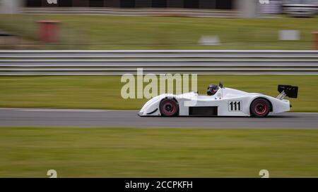 Une photo panoramique d'une voiture de course blanche en circuit sur une piste. Banque D'Images