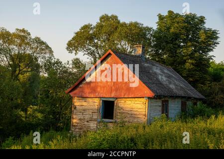 Une ancienne maison en bois abandonnée avec un toit recouvert de ciment d'amiante très nocif Banque D'Images