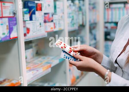 Pharmacien tenant des boîtes de médicaments et des capsules en pharmacie. Banque D'Images