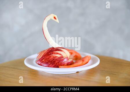 La pomme en forme de sculpture fait un oiseau ou un cygne sur une assiette blanche / sculpture de fruits Banque D'Images