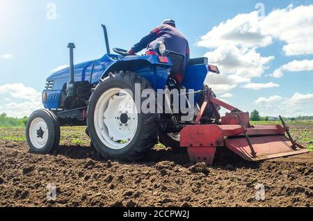 Un agriculteur qui travaille sur un tracteur équipé d'une fraiseuse perd le sol dans le champ de la ferme. Préparation pour la plantation de nouvelles récoltes. Meuler et mélanger le sol sur le plantati Banque D'Images