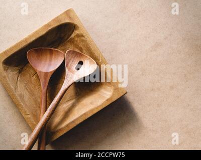 Ustensiles de cuisine en bois sur une assiette en bois faite à la main sur un fond de papier kraft. Produits naturels ou concept alimentaire, vue de dessus, plat. Banque D'Images