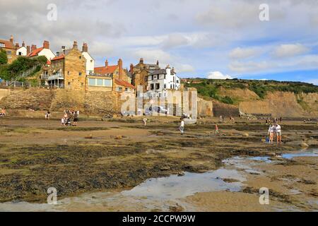 Touristes sur le front de mer à marée basse à Robin Hoods Bay, North Yorkshire, North York Moors National Park, Angleterre, Royaume-Uni. Banque D'Images