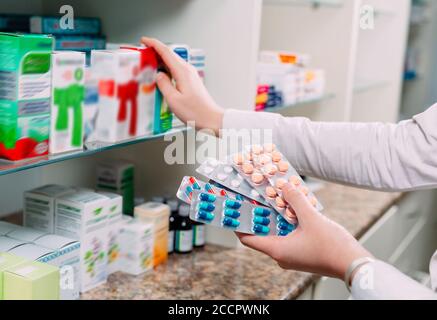 Pharmacien tenant des boîtes de médicaments et des capsules en pharmacie. Banque D'Images