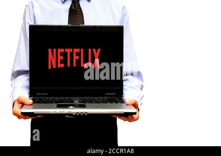 Homme tenant un ordinateur portable avec le logo de Netflix streaming service à l'écran Banque D'Images