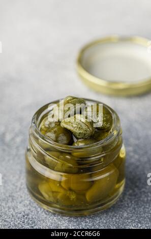 Gros plan sur les câpres marinées ou salées dans un pot en verre. Boutons floraux non ouverts. Délicieux ingrédients pour la cuisine méditerranéenne, italienne, espagnole, française cuis Banque D'Images