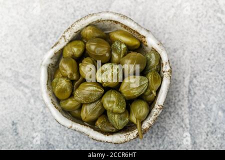 Gros plan sur des câpres marinées ou salées dans un bol en céramique. Boutons floraux non ouverts. Ingrédients délicieux pour la cuisine méditerranéenne, italienne, espagnole, française c Banque D'Images