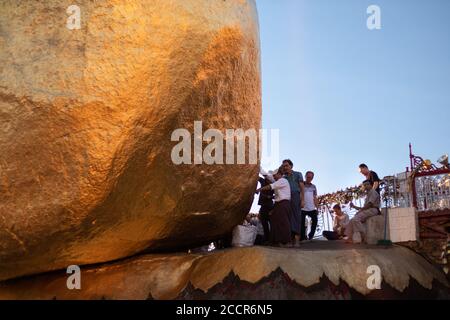 Hommes qui collent des feuilles d'or à la Pagode Kyaiktiyo - Golden rock. Garde regardant le rock. Lieu de pèlerinage bouddhiste sacré dans l'Etat mon, Myanmar, Asie Banque D'Images