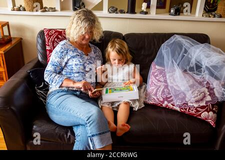 Jeune enfant femme de 3 ans jouant sur une pomme IPad Air avec sa grand-mère Banque D'Images