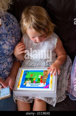 Jeune enfant femme de 3 ans jouant sur une pomme IPad Air Computer avec sa grand-mère Photographie prise par Simon Dack Banque D'Images