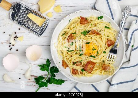 Pâtes Carbonara. Spaghetti au bacon, aux œufs, au persil et à la sauce au parmesan dans une assiette blanche sur une table en bois. Cuisine méditerranéenne traditionnelle (italienne) Banque D'Images