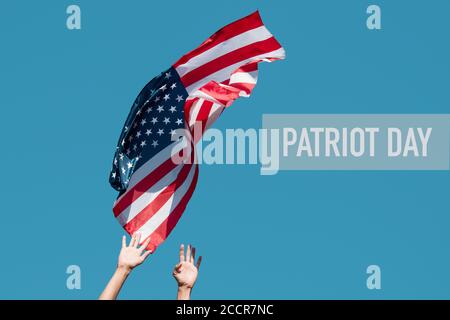 gros plan d'un jeune homme caucasien lançant un drapeau des États-Unis au ciel bleu, ou sur le point de le capturer du ciel, et le texte patriote jour Banque D'Images